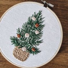 a cross stitched christmas tree with pine cones and fir needles on a white hoop