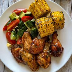 grilled chicken, vegetables and corn on the cob are served on a white plate