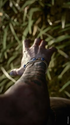 a person with tattoos on their arm and wrist is laying down in the grass looking at something