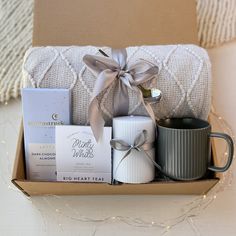 a gift box with coffee mugs, tea bags and other personal items in it