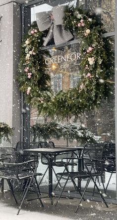 an outdoor dining area with tables and chairs covered in wreaths on the side of a building