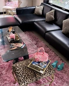 a living room filled with black couches and leopard print rug on top of a pink area rug