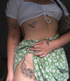 a woman with tattoos on her stomach wearing a skirt