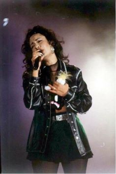 a woman standing in front of a microphone and wearing a black jacket with studs on it