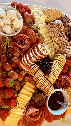 a platter filled with cheeses, crackers, fruit and other food items