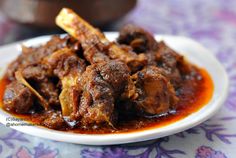 a close up of a plate of food with meat and sauce on the tablecloth