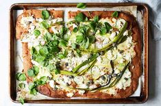 a square pizza topped with green vegetables and feta cheese