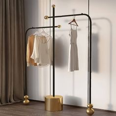 two clothes are hanging on a rack in front of a window with drapes and curtains