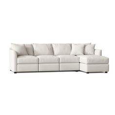 a white sectional couch with pillows on it's back and the seat folded out