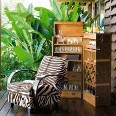 a zebra print chair sitting on top of a wooden floor next to a cabinet filled with wine glasses