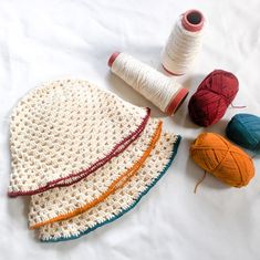 three balls of yarn and two skeins of thread on a white surface,