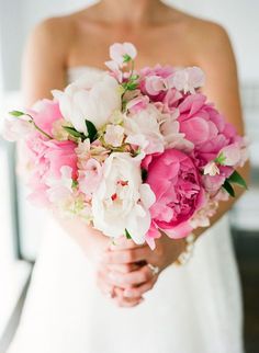 a bride holding a bouquet of pink and white flowers