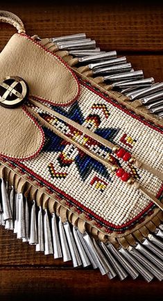 a cross stitch purse sitting on top of a wooden table next to some metal rods