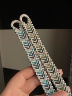 a hand holding a pair of scissors made out of woven material with blue, green and white stripes