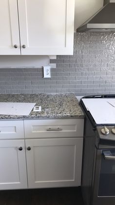 a stove top oven sitting inside of a kitchen next to white cabinets and counter tops