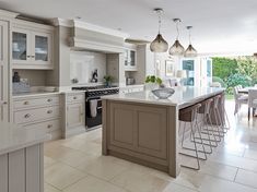 a large kitchen with white cabinets and an island in front of the stove top oven