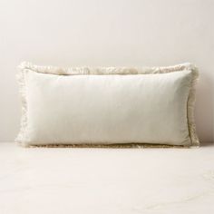 a white pillow sitting on top of a table next to a wall with a light colored background