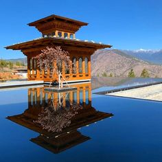 a reflection of a building in the water with mountains in the backgrouds