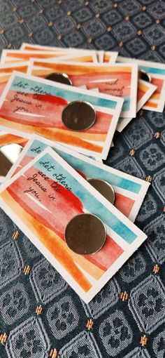 four different colored tags on top of a blue and black table cloth with silver buttons