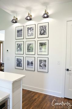 a kitchen with white cabinets and pictures on the wall