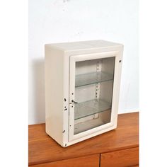 an empty white cabinet sitting on top of a wooden table