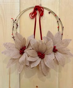 a wreath with red berries and white flowers hanging on a wall