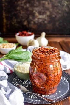 a glass jar filled with sauce sitting on top of a plate next to other dishes