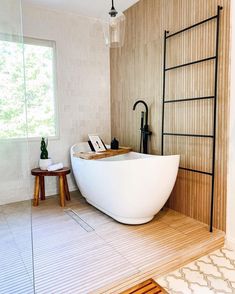 a large white bath tub sitting in a bathroom next to a wooden table and stool