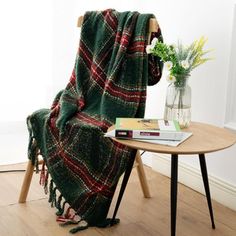 a green and red blanket sitting on top of a wooden chair next to a table