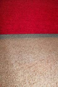 a red couch sitting on top of a carpeted floor