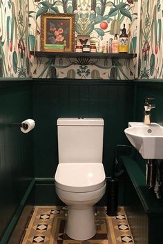 a toilet and sink in a small room with wallpaper on the walls behind it