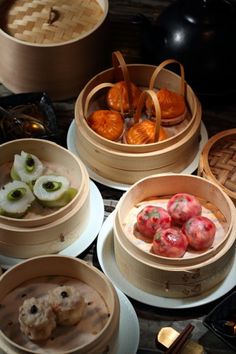 several wooden containers filled with food on top of a table next to other bowls and utensils