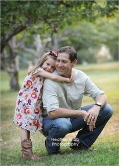 a father and daughter hugging each other in the grass