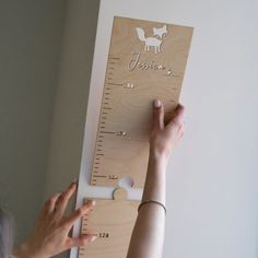 a woman is measuring the height of a wooden growth chart with her hands on it