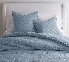 a bed with blue comforters and pillows on it