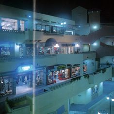 an aerial view of a building at night with lights on and people in the windows