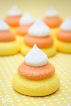 there are many small cookies with white and orange frosting on them, sitting on a yellow tablecloth