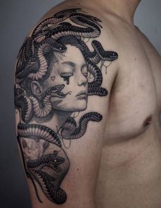 a man with a tattoo on his arm and shoulder is holding a snake in front of him