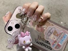 a person holding a cell phone case with a hello kitty keychain attached to it