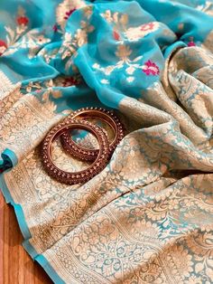 This is a pure khaddi georgette banarasi saree in light blue color with meenakari and golden zari weave. Saree features a contemporary and spacial floral jaal using vibrant colors and golden zari in the body of the saree. Golden zari floral motif with floral jaal is intricately woven in the pallu, the pallu is finished with ultra-fine tassels in multicolor. Paisleys and floral design in a structural pattern are compactly woven in the border of the saree. This is paired with a plain blouse with a Celebration Georgette Traditional Wear With Self Design, Traditional Brocade Saree, Traditional Wear With Motifs For Festive Season, Transitional Festive Traditional Wear With Motifs, Banarasi Silk Sets With Motifs For Eid, Transitional Paithani Silk Sets With Dupatta, Eid Brocade Sets With Motifs, Festive Paithani Silk Set For Eid, Brocade Sharara For Traditional Ceremonies