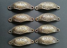 six antique brass drawer pulls with ornate designs