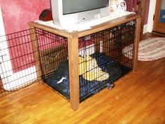 a computer monitor sitting on top of a wooden desk next to a dog cage filled with clothes