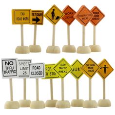 various road signs are arranged in rows on wooden sticks with white bases and wood posts