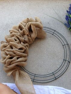 a wreath made out of burlocks on the ground next to some blue flowers