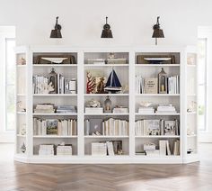 a white bookcase filled with lots of books on top of a hard wood floor