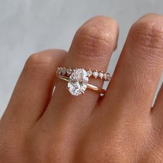 a woman's hand with a diamond ring on top of her finger and an engagement band