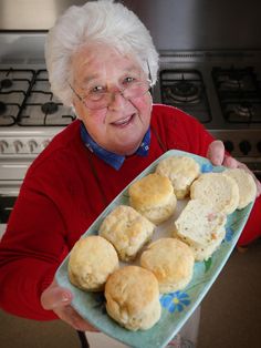 an elderly woman holding a plate of biscuits