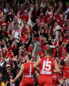 a large group of people in red and white uniforms are cheering for the basketball team