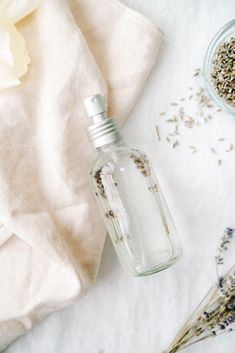 a glass bottle filled with lavender oil next to some dried flowers and a white towel