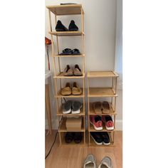 several pairs of shoes sitting on top of a wooden shelf next to a white wall